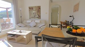 Un salón con sofá, mesa de centro y mesa de comedor con fruta.