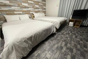 A hotel room with two beds, a wooden headboard, a television on a stand, and a curtain.