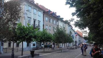 A street lined with historic buildings, trees, and a few pedestrians.