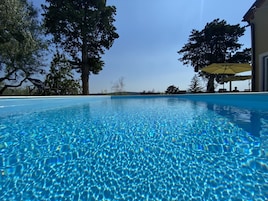 A clear blue pool with a view of trees and a building in the background.