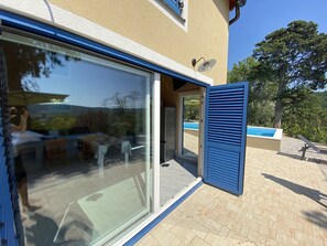 A modern building with a glass door leading to a patio area.