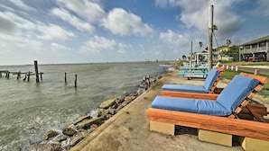Uitzicht op het strand met houten ligstoelen en een pier op de achtergrond.