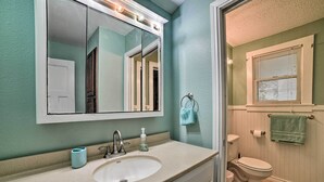 Een badkamer met een wastafel, spiegel, toilet en raam.