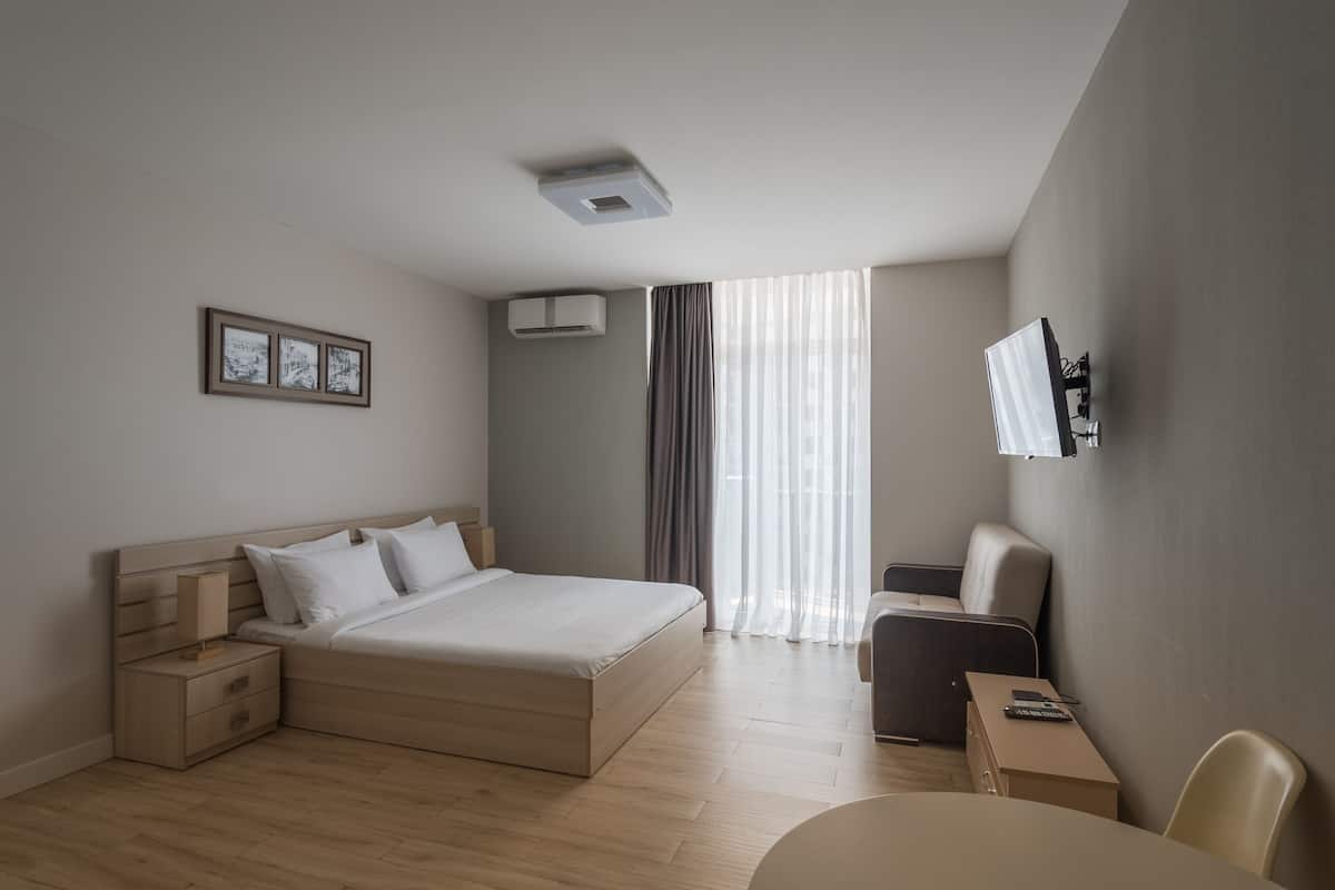 A modern hotel room with a large bed, bedside tables, a desk, and a chair.