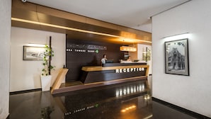 A modern reception area with a reception desk, a wooden staircase, and a framed picture on the wall. - Orbi Sea Towers Hotel Official (Batumi)