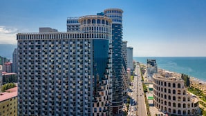 A high-rise building with a modern architectural design, featuring multiple balconies and a prominent curved structure at the top. - Orbi Sea Towers Hotel Official (Batumi)