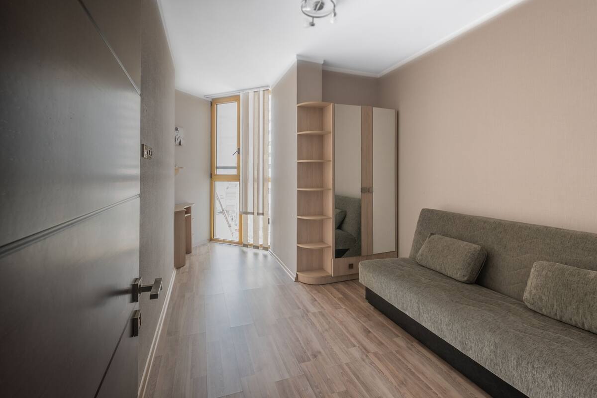Una sala de estar moderna con sofá, armario empotrado y puerta corrediza de vidrio que da a un balcón.