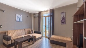 A modern living room with a sofa, a coffee table, and a TV stand. - Orbi Plaza Hotel Official (Batumi)