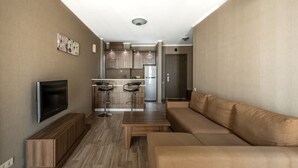 A modern living room with a sofa, a TV, and a wooden coffee table. - Orbi Plaza Hotel Official (Batumi)