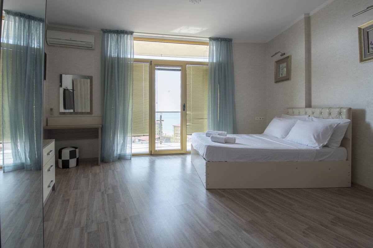 Un dormitorio con cama, cómoda, espejo y ventana con cortinas.