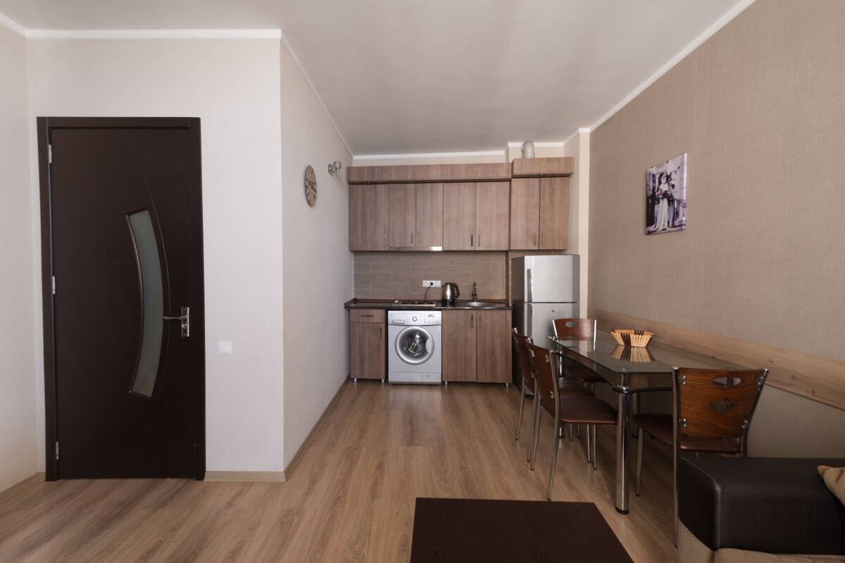 Una cocina compacta con lavadora, un comedor con mesa y sillas, y una puerta oscura.