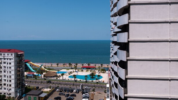 A high-rise hotel overlooking a beach with a water park, a pool, and a parking lot. - Orbi Plaza Hotel Official (Batumi)
