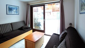 A living room with a sofa, a wooden coffee table, and a view of a building through a large window.