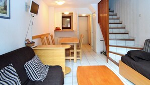 A compact living space with a sofa, a dining table, and a staircase.