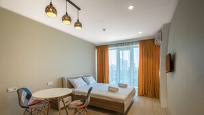 A modern hotel room with a bed, a dining table, two chairs, and a TV. - Orbi Beach Tower Hotel Official (Batumi)