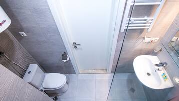 Un baño moderno con inodoro, lavamanos y cabina de ducha con mampara de vidrio.