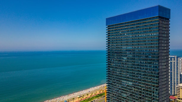 A high-rise building with a modern glass facade overlooking a beach. - Orbi Beach Tower Hotel Official (Batumi)