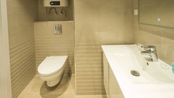 Een moderne badkamer met toilet, wastafel en douche.