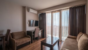 A modern living room with a sofa, a coffee table, and a TV on a stand. - Orbi Beach Tower Hotel Official (Batumi)