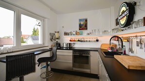 A modern kitchen with stainless steel appliances, a black countertop, and a window providing a view of the outside. - Sunny 4 room apartment near the lake with south-facing roof terrace
 (Eriskirch)