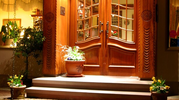 A hotel entrance with a wooden facade, double doors, and a sign above the doors. There are potted plants on either side of the entrance. - Ferienwohnung im Landhotel Sonneneck (Breuna)