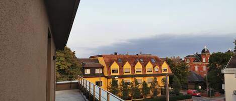 A balcony with a view of a yellow building with multiple windows and a red building with a dome in the background.