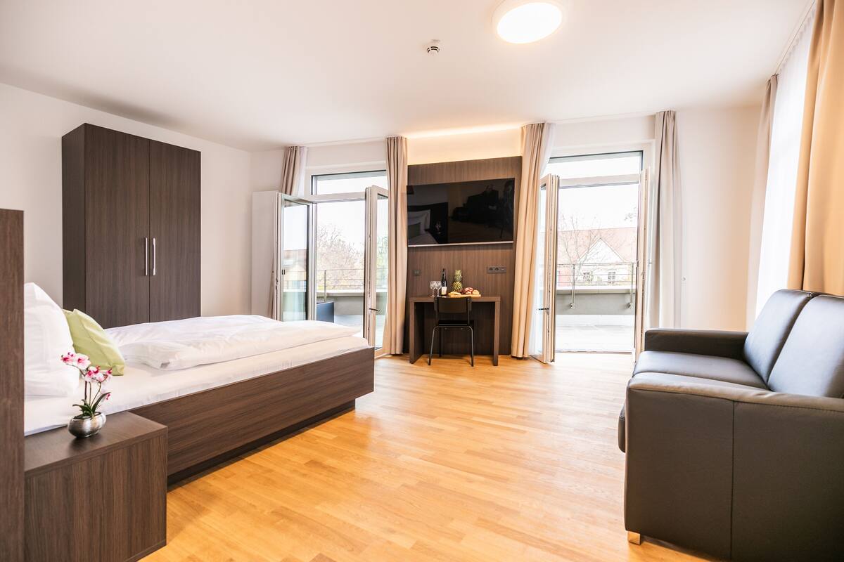 A modern bedroom with a bed, a desk, and a sofa.