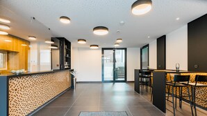 Un moderno vestíbulo de hotel con mostrador de recepción, zona de estar y una escalera que conduce a los pisos superiores.