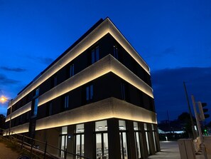 A modern building with a unique angular design, featuring large windows and a well-lit facade. - GuestHouse Speyer (Speyer)