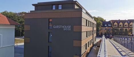 Un edificio moderno con techo plano y varias ventanas, identificado con el cartel 'GUESTHOUSE SPAYER'.