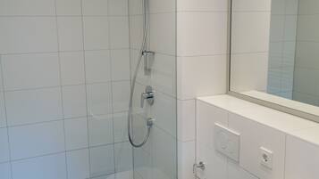 A modern bathroom with a glass-enclosed shower, a white sink, and a large mirror.