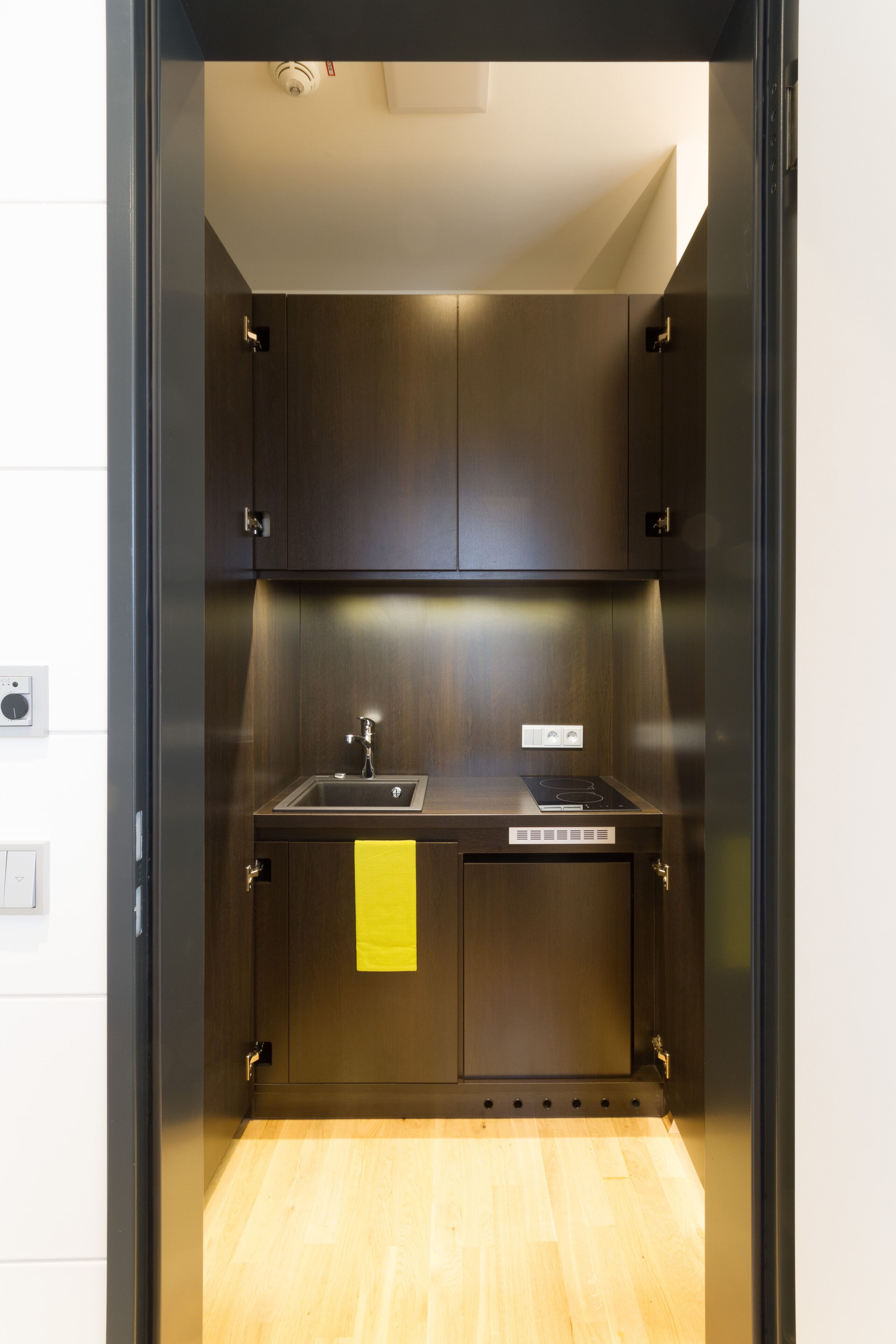 A compact kitchen with dark cabinetry, a stainless steel sink, and a built-in stove.