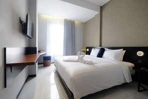 Una habitación de hotel moderna con una cama grande, un escritorio y un televisor montado en la pared.