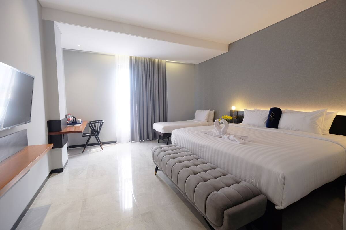 A modern hotel room with a large bed, a desk, and a TV.