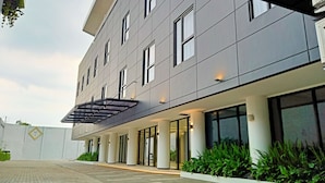 A modern building with a flat facade, large windows, and a covered entrance area. - Hotel Youstay Semarang By Sinergi (Semarang)