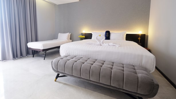 A modern hotel room with a large bed, two bedside tables, and a bench. - Hotel Youstay Semarang By Sinergi (Semarang)