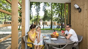 A wooden pergola with a table and chairs, a basket of fruit, and a watermelon on the table. - Barack Thermal Apartments (Tiszakécske)