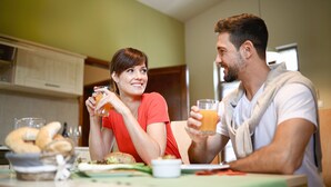 A couple sitting at a table with breakfast items, including a basket of rolls and a glass of orange juice. - Barack Thermal Apartments (Tiszakécske)