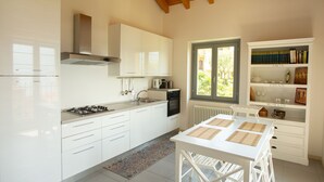 Una cocina moderna con armarios blancos, una estufa a gas y una ventana con vistas a un jardín.