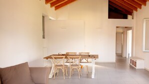Amplia sala de estar con techo de madera alto, una mesa de comedor de madera con sillas, un sofá color beige y una mesa de centro con revistas.
