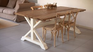 Una mesa de madera con cuatro sillas, una cesta tejida y una base blanca.