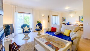 A living room with a sofa, armchairs, a coffee table, and a television.