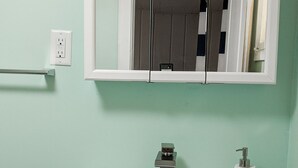Une salle de bain avec un lavabo blanc, un miroir au-dessus et un porte-serviettes à gauche.