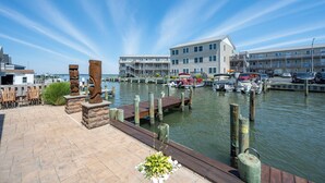 A marina with docked boats, a wooden walkway, and buildings in the background. - Outdoor Living At it's Finest With this Vacation Home! (Ocean City)