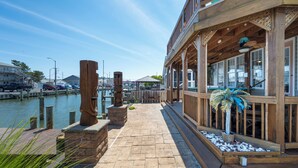 A waterfront walkway with a wooden deck, stone steps, and a view of the marina. - Outdoor Living At it's Finest With this Vacation Home! (Ocean City)