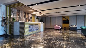 A modern reception area with a marble floor, a reception desk, and a seating area with sofas. - Grand Merpond Otel (Merzifon)