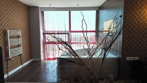 A modern bathroom with a large window, a bathtub, and a radiator. - Grand Merpond Otel (Merzifon)