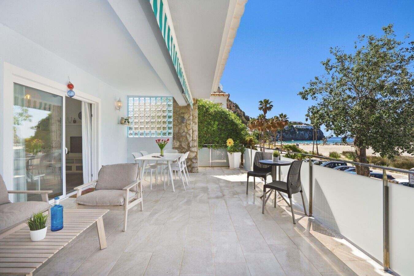 A balcony with a dining area, seating, and a view of the beach.