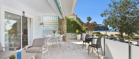 A balcony with a dining area, seating, and a view of the beach.