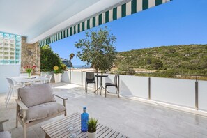 Un balcon avec des sièges d’extérieur, une vue sur la mer et un mur en pierre.